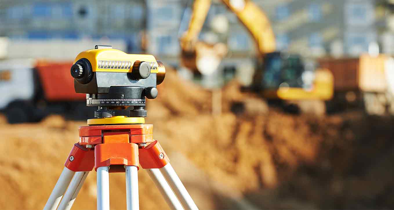 Optical survey level on a tripod at an excavation site