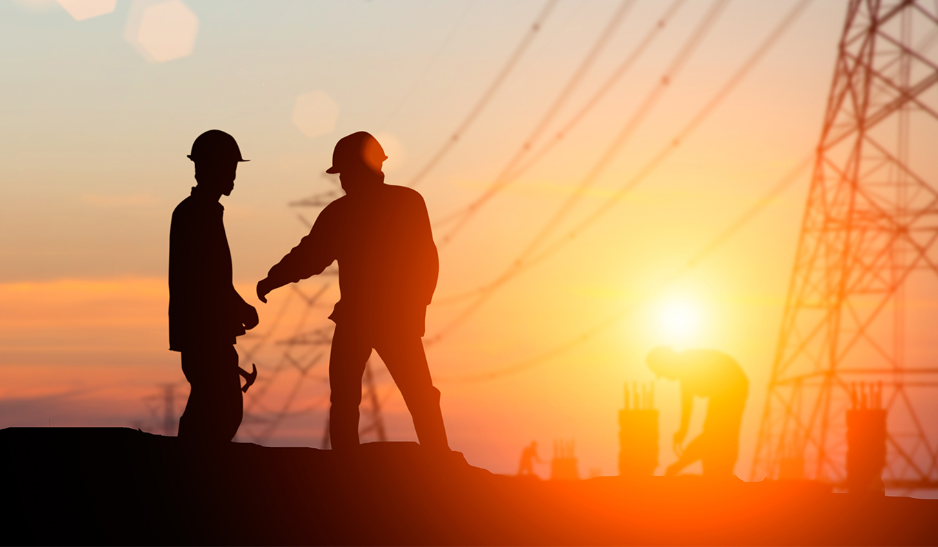 Field workers silhouetted beside transmission lines